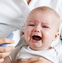 Nurse Taking Crying Baby's Temperature With Digital Thermometer