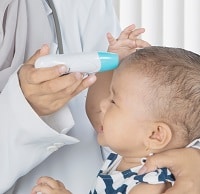 Pediatrician examining temperature of baby