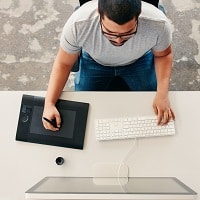 Graphic designer using digital graphics tablet and desktop