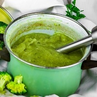 Mixing blender in pot with broccoli soup.